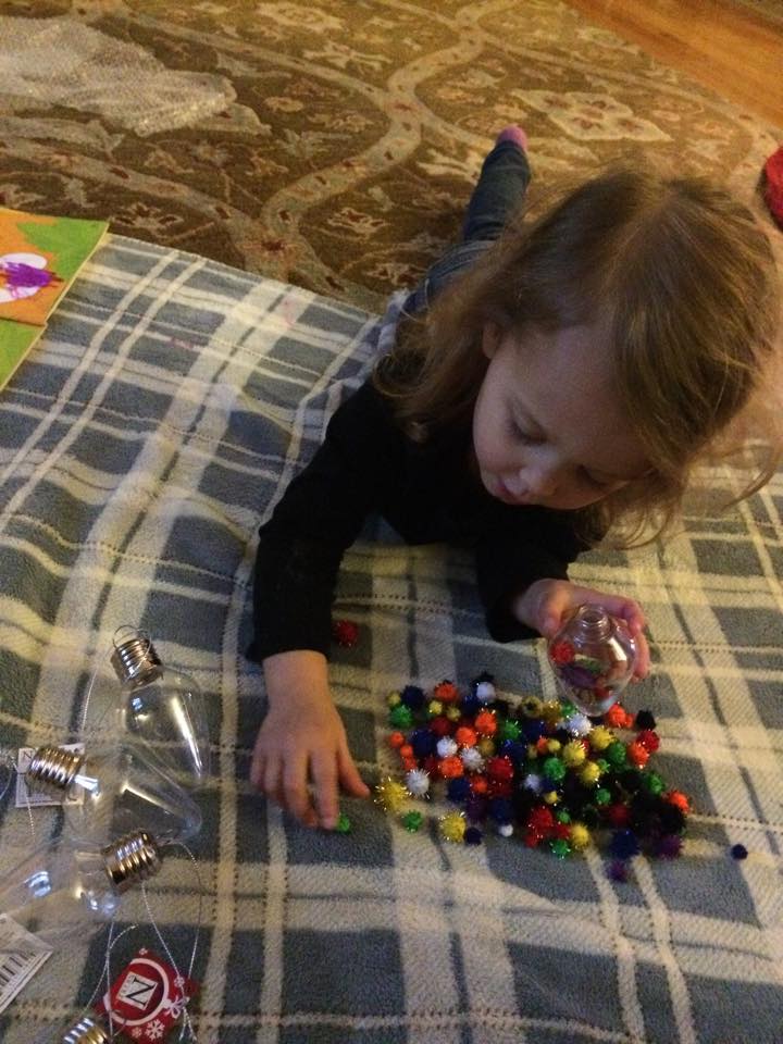 G stuffing the pom poms into the ornament