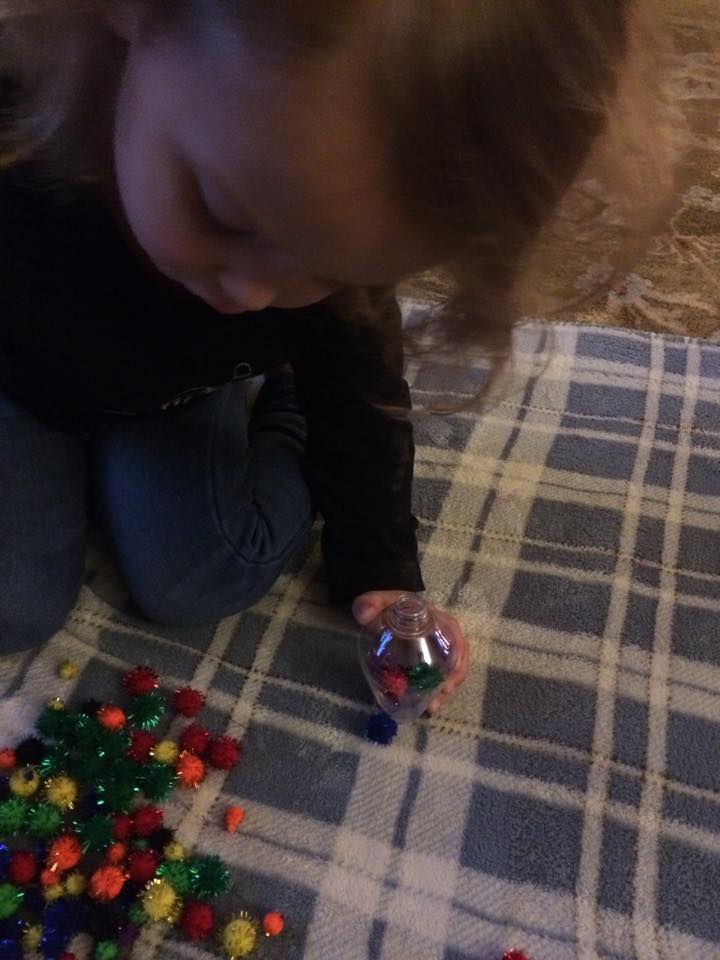 G working on her fine motor skills stuffing the ornament